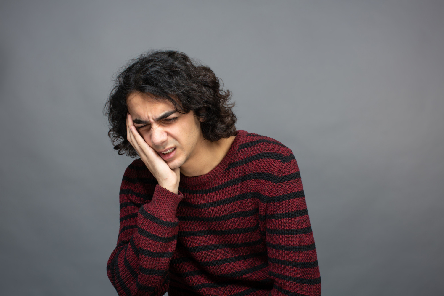 Man holding jaw in pain during wisdom teeth removal recovery