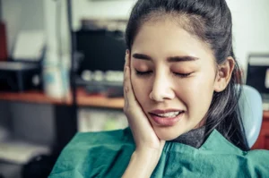 Woman with painful wisdom tooth infection holding her cheek