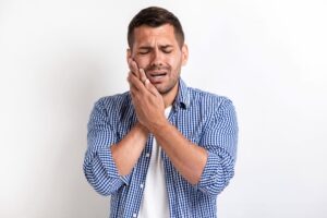 Person suffering from intense wisdom tooth pain holding their jaw in discomfort