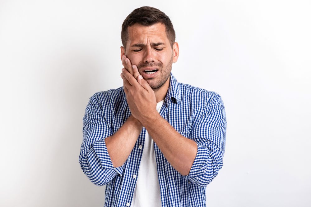 Person suffering from intense wisdom tooth pain holding their jaw in discomfort